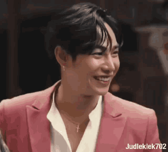 a man wearing a pink suit and a white shirt is smiling .