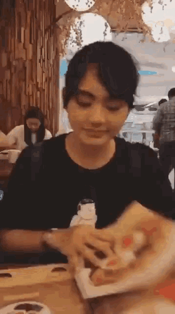 a person is sitting at a table eating a sandwich .
