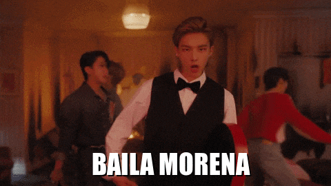 a man in a tuxedo is dancing in a room with the words baila morena on the bottom