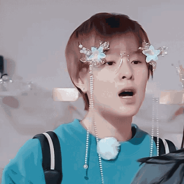 a person wearing a blue shirt and a necklace with pearls and flowers on it
