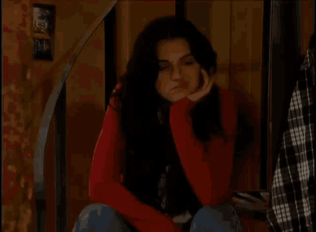 a woman in a red sweater is sitting on a set of stairs and smiling .
