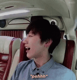 a man in a blue shirt is sitting in a car with his mouth open and says " pshhh "