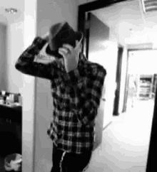 a man in a plaid shirt is taking a picture of himself in a mirror