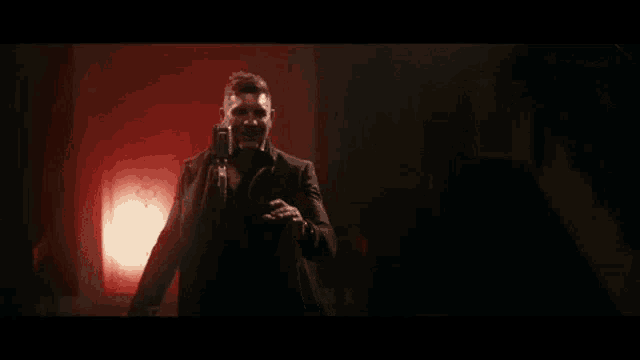 a man in a suit and tie is singing into a microphone in a dark room .