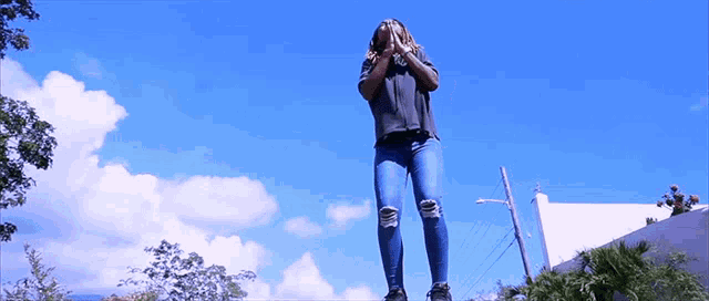 a woman covering her face with her hands while standing on a ledge