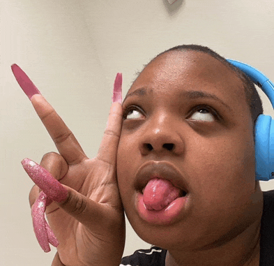 a woman with long pink nails and headphones sticking her tongue out