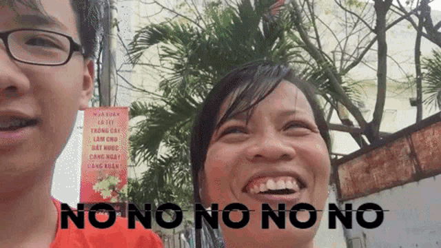 a man and a woman are smiling in front of a no no no no sign
