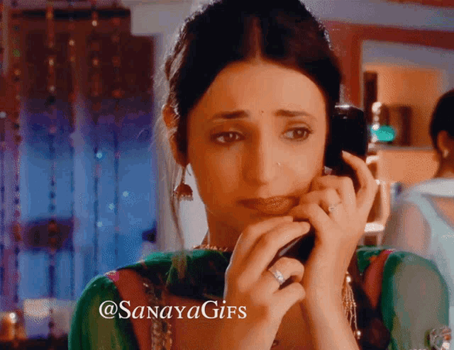 a woman crying while talking on a cell phone with a watermark that says sanayagifs