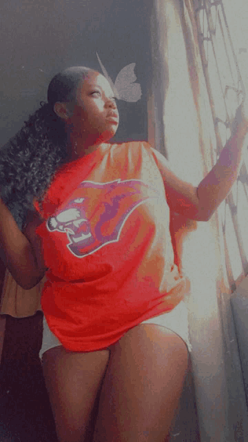 a woman wearing a red buccaneers shirt looks out a window