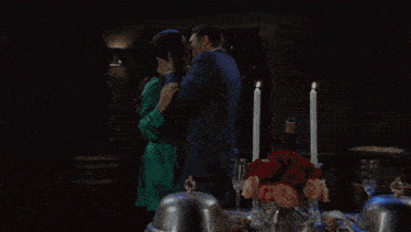 a man and a woman are hugging in front of a table with candles