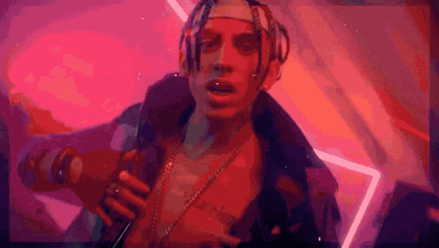a man with dreadlocks is singing into a microphone with a tattoo on his chest