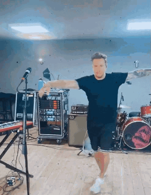a man in a black shirt is dancing in front of a drum set with a skull on it