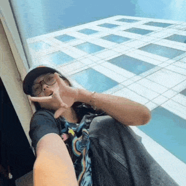a person wearing glasses and a hat is sitting in front of a window