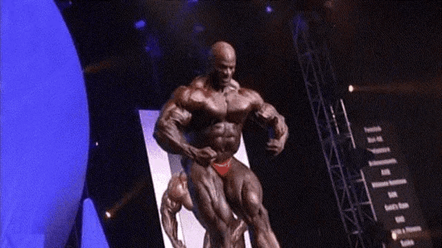 a bodybuilder in a red bikini is standing on a stage in front of a blue ball .