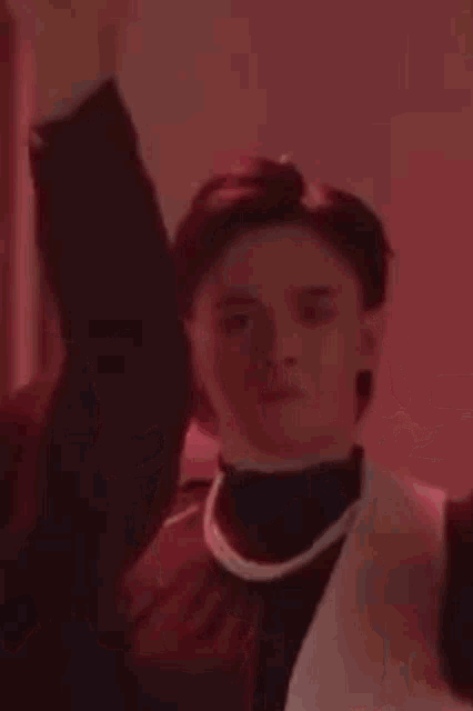 a group of people are dancing in a room in front of a red light .