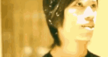 a close up of a person 's face with a yellow background and a black shirt .