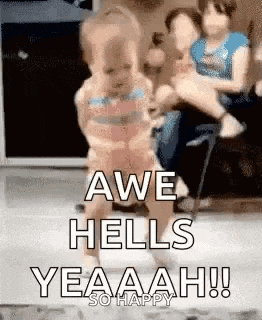 a baby is dancing in a living room with a woman holding a baby in the background .