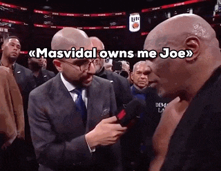 a man in a suit and tie is talking to a bald man in a boxing ring