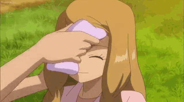 a girl is holding a towel to her forehead while sitting in the grass .