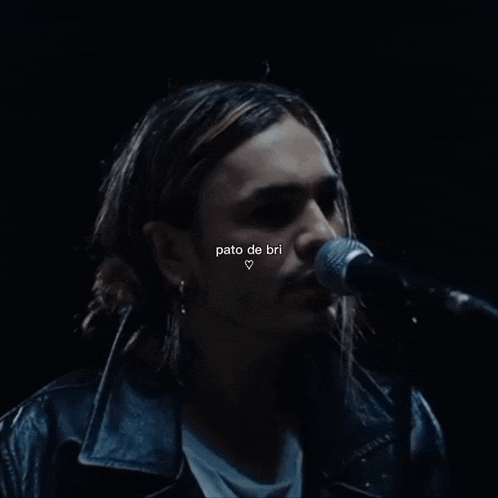 a close up of a man singing into a microphone with pato de bri written above him