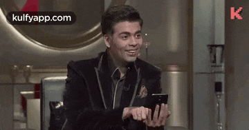 a man is laughing while holding a cell phone in his hands .