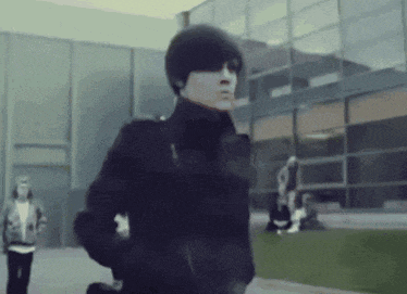 a person in a black jacket is walking in front of a building