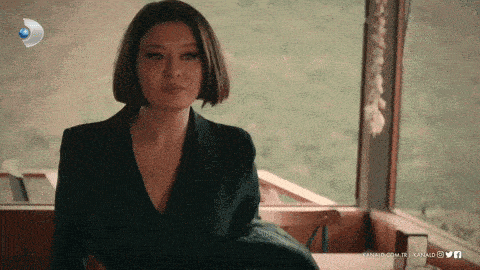 a woman in a black suit is sitting in front of a window with the words kanal5.com.tr written on the bottom