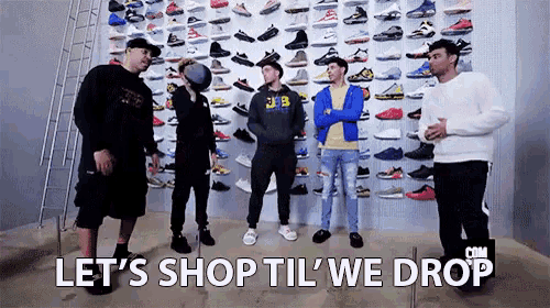 a group of men are standing in front of a wall filled with sneakers .