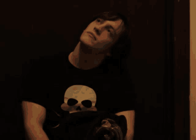 a young man wearing a black shirt with a white skull on it