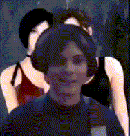 a man wearing headphones stands in front of a woman in a red tank top