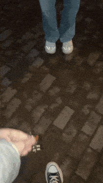 a person holding a pair of scissors on a brick sidewalk