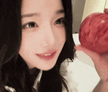 a close up of a woman 's face with an apple in her hand