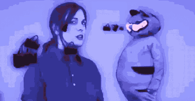 a woman in a blue shirt stands next to a cartoon character