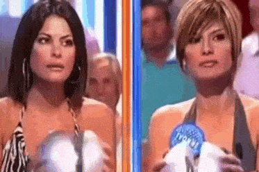 two women are standing next to each other on a stage holding a microphone .