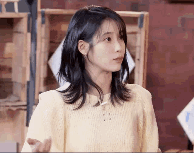 a woman wearing a yellow sweater is standing in front of a wooden box