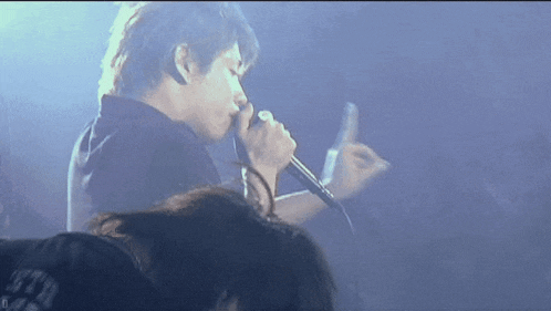 a man singing into a microphone while wearing a black shirt that says ' t.f.u. '