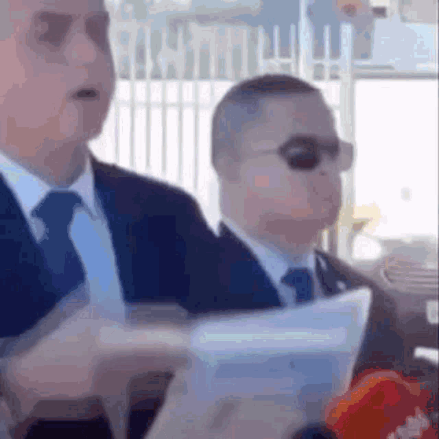 a man in a suit and tie is holding a piece of paper in his hand .