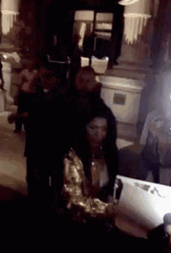 a woman is standing in a dark room with a laptop on her lap