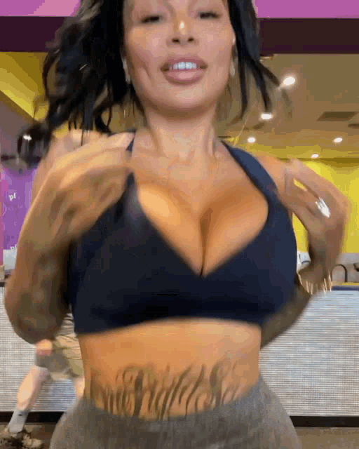 a woman with a tattoo on her stomach is wearing a blue sports bra