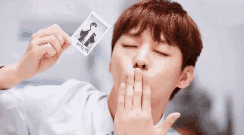 a man is blowing a kiss while holding a polaroid picture .