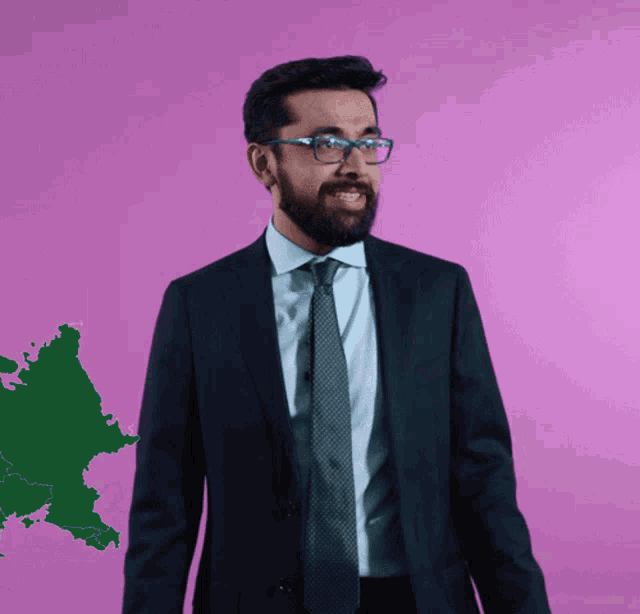 a man in a suit and tie is smiling in front of a pink background