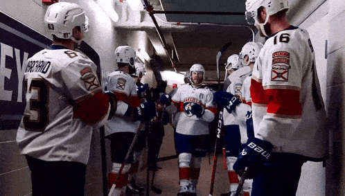 a group of hockey players are standing in a locker room and one has the number 9 on his jersey