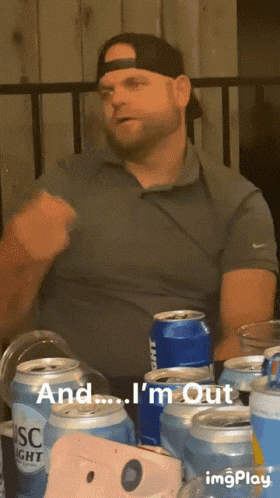 a man sitting at a table with a bunch of beer cans and the words and i 'm out