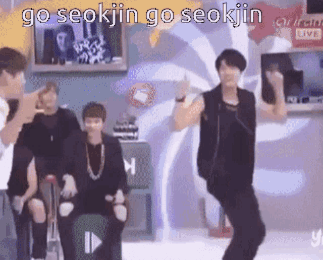 a group of men are dancing in a room with the words go seokjin go seokjin written on the bottom .