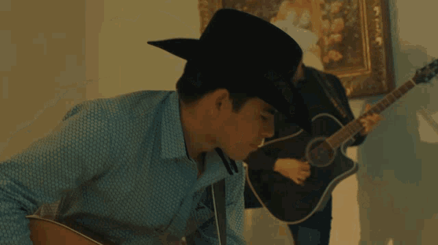 a man in a cowboy hat plays a guitar