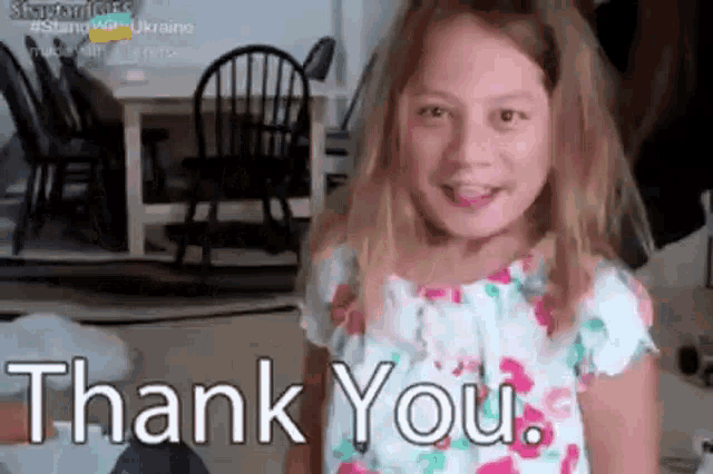 a little girl is smiling and saying `` thank you '' in a living room .