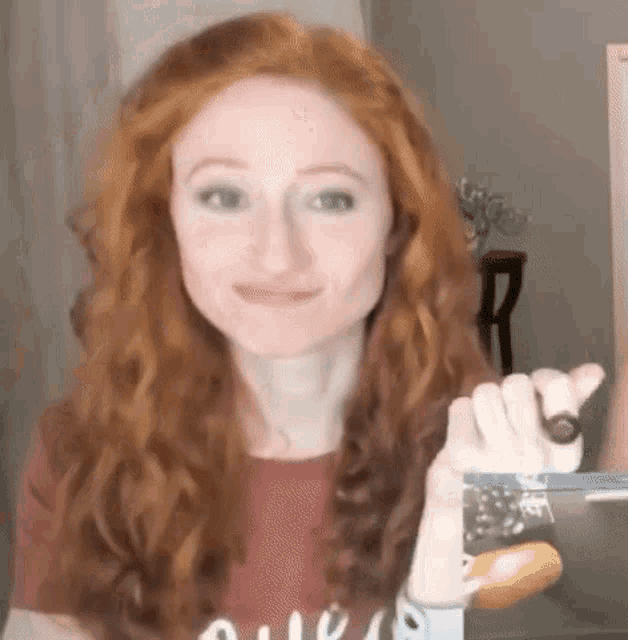 a woman with red hair is holding a pair of scissors .