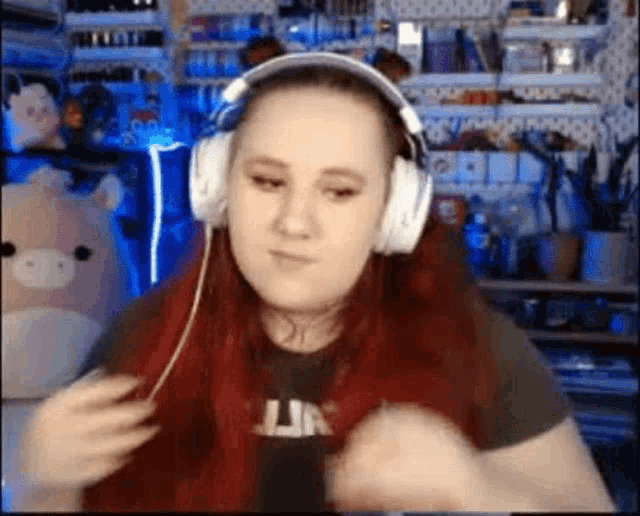a woman with red hair is wearing headphones and making a face .