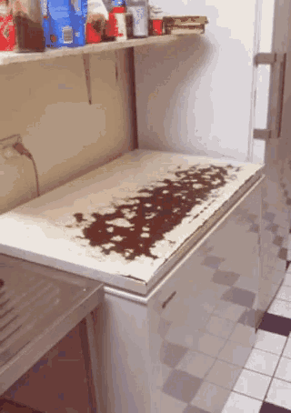 a dirty freezer in a kitchen with a shelf behind it that has a bag of ice cream on it