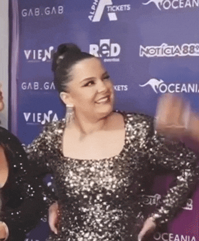 a woman in a sequined dress is standing on a purple carpet in front of a blue wall .